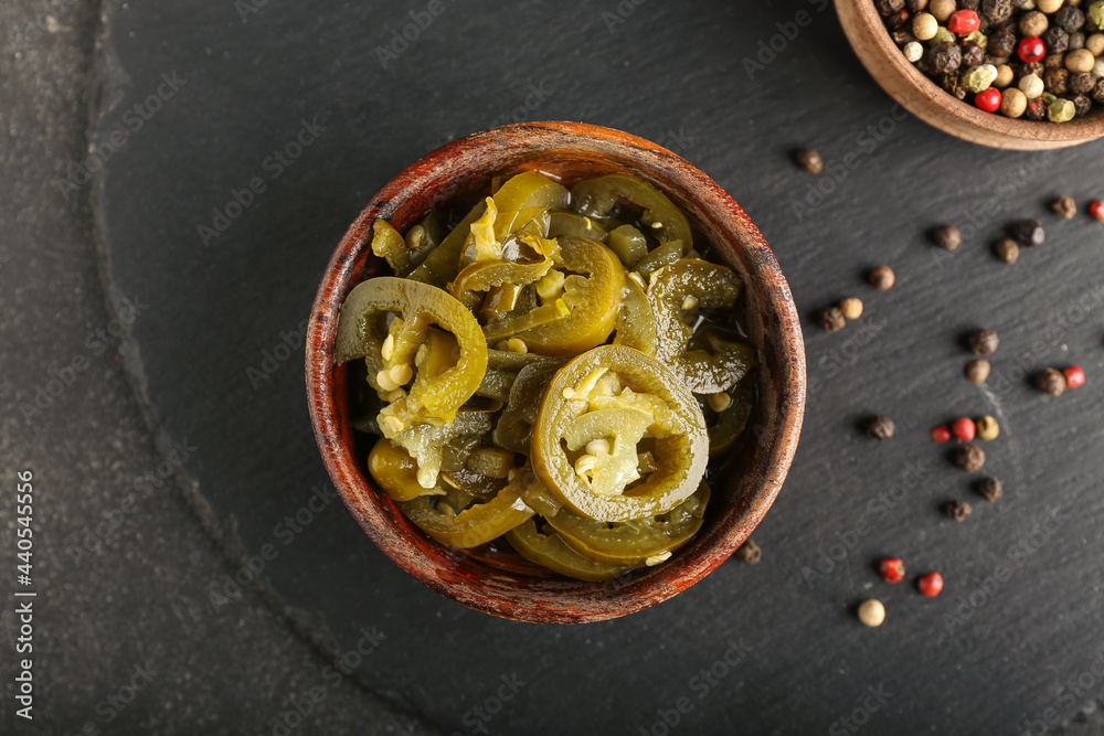 Bowl with canned jalapeno on dark background