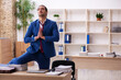 © Elnur - Young male employee doing yoga exercises during break