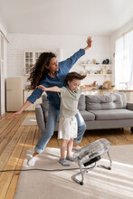 Carefree Mom And Kid Have Fun At Home Play With Wind From Ventilator, Indoor Air Fan Cheering And Bonding. Overjoyed Young Parent, Millennial Female Enjoy Leisure Activity With Small Son On Lockdown
