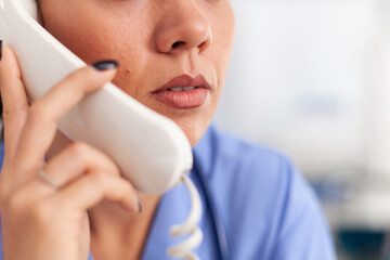 Wall Mural - Medical receptionist answering phone calls from patient in hospital. Female nurse, doctor having a phone conversation with sick person during consultation, medicine.