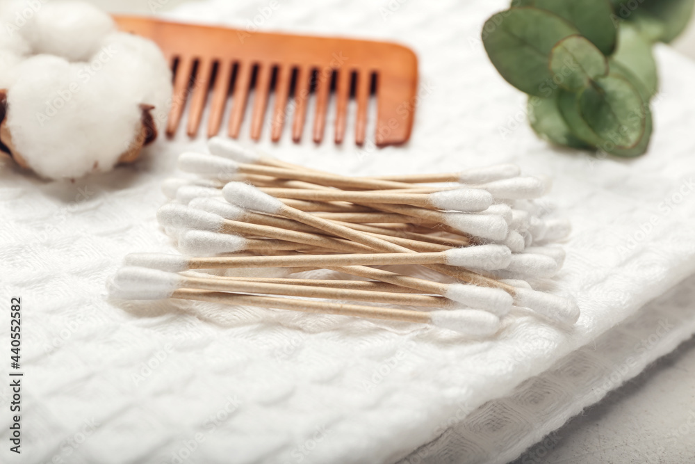 Cotton swabs, flower and comb on towel, closeup