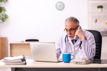 Wall Mural - Aged male doctor working in the clinic