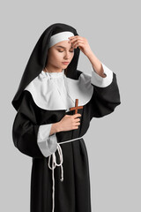 Wall Mural - Young praying nun on light background