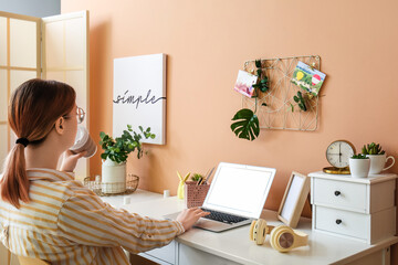 Poster - Young woman working on laptop at table in room