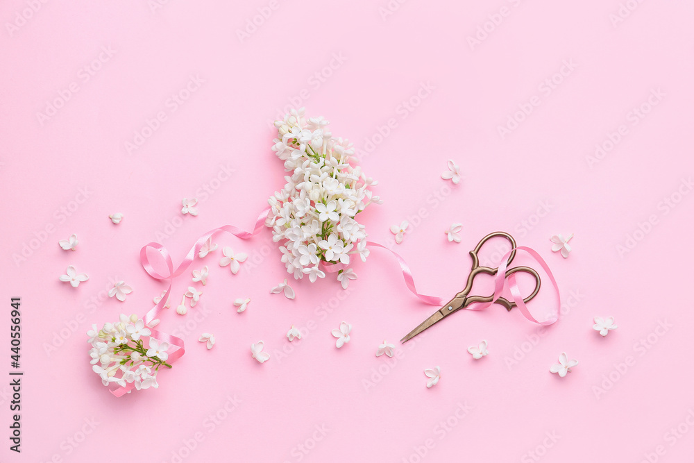 Beautiful lilac flowers, scissors and ribbon on color background