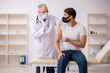 © Elnur - Young male patient visiting old doctor in vaccination concept