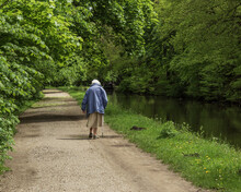 A Senior Lady Enjoying A Leisurely Walk Along The Tow Path Of The Leeds And Liverpool Canal At Shipley West Yorkshire