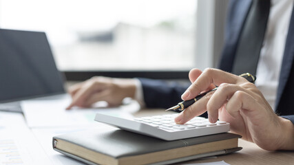 Businessman presses a calculator to calculate earnings and analyze company earnings in his private office, Information in finance and accounting, Company performance and revenue.