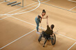 © Seventyfour - Wide angle view at young sportswoman in wheelchair playing badminton and high five partner during practice at indoor court, copy space