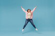 © ViDi Studio - Full length young joyful smiling redhead chubby overweight woman 30s wearing in pink shirt jeans jumping high with oustretched hands looking camera have fun isolated on pastel blue background studio.