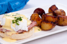 Closeup Shot Of Eggs Benedict With Farm Fresh Eggs And Ham And Fried Potatoes