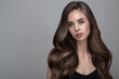 © Alena - Portrait of a woman with long brown large curls. On a gray background