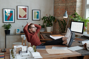 Wall Mural - Relaxed architect looking at monitor with sketch