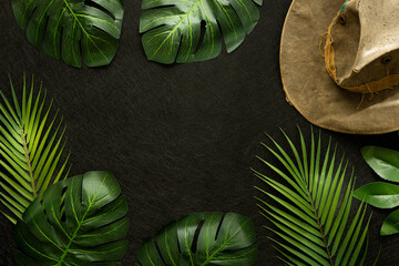 Fototapete - Big Tropical Jungle Leaves, Old Travel Hat, Creative Concept, Round the World Travel, Discovery Expedition, Minimal Layout, Black Background, Space for Text