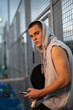 © FotoAndalucia - Young man with urban style takes a break with the phone trains after playing paddle tennis on an outdoor court