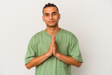 Young venezuelan man isolated on white background praying, showing devotion, religious person looking for divine inspiration.