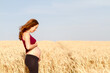 © Juan - pregnant woman in red in a wheat field relaxing in nature