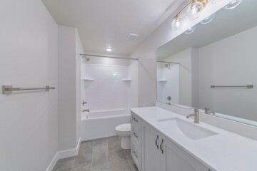 Sticker - Interior of a white bathroom with a bathtub, white sink with drawer and a big mirror