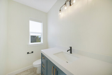 Sticker - Interior of a restroom with a white sink, blue drawer and a flush toilet next to a small window