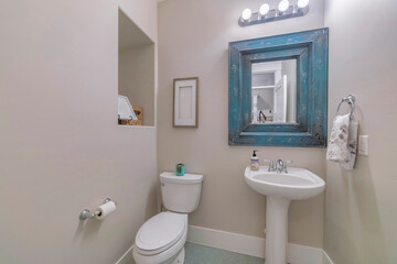 Wall Mural - Interior of a restroom with a flush toilet, white sink and a blue retro mirror