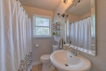 Sticker - Bathtub with a closed curtain, sink, mirror and a flush toilet in a bathroom with a small window