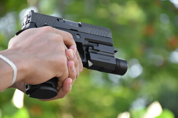 automatic 9mm pistol holding in hands, aiming to the shooting target and ready to shoot, concept for security profession and bodyguard training around the world, selective focus and blurred background