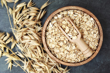 Wall Mural - Oatmeal in wooden spoon on oat ears plants background, selective focus, toned	