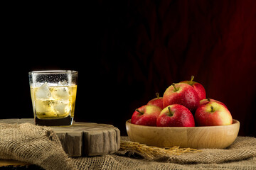 Wall Mural - Apple juice in a champagne glass and apples in a wooden bowl on vintage background