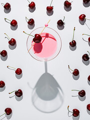 Wall Mural - Fresh cherries and a glass of a cherry cocktail in the middle isolated on a bright white background. Creative summer fruit drink concept. Top view.