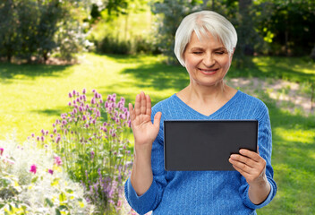 Wall Mural - technology, gardening and old people concept - smiling senior woman using tablet computer having video call and waving hand over summer garden background