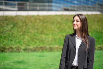 Wall Mural - Smiling young woman near a grass field and a glass office building