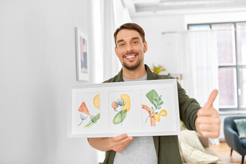 Wall Mural - home improvement, decoration and art concept - happy smiling man holding watercolor picture in frame