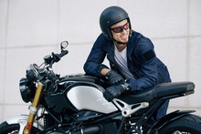 Portrait Of Happy Smiling Man In Helmet Leaning On Motorcycle And Looking Away
