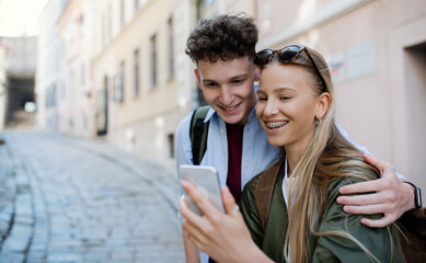 Wall Mural - Young couple travelers with smartphone in city on holiday, sightseeing.