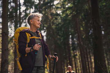 Senior woman hiker outdoors walking in forest in nature, walking.