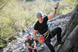 © Halfpoint - Senior man with instructor climbing rocks outdoors in nature, active lifestyle.