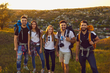 Wall Mural - portrait of young friends with rucksacks looking at camera in mountains. team of millennial tourists