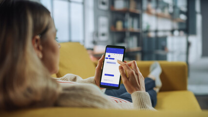 Poster - Beautiful Authentic Female Using a Smartphone with Calendar Application at Home Living Room while Lying on a Couch Sofa. She's Making Plans and Checking Event Schedule for a Day.