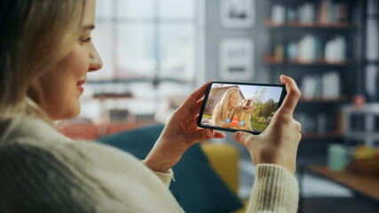 Fototapete - Close Up of a Female Chatting in a Video Call with Her Beautiful Friend Playing with a Dog on Smartphone from Home Living Room. Freelancer Chatting with a Client on a Call Over the Internet.
