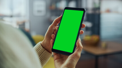 Aufkleber - Close Up of an Authentic Female Using Smartphone with Green Screen Mock Up Display at Home Living Room while Lying on a Couch Sofa. She's Browsing the Internet and Checking Videos on Social Networks.