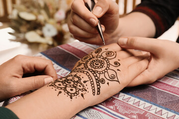 Master making henna tattoo on hand, closeup. Traditional mehndi