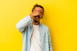 © Asier - Young caucasian man with long hair isolated on yellow background covers eyes with hands, smiles broadly waiting for a surprise.