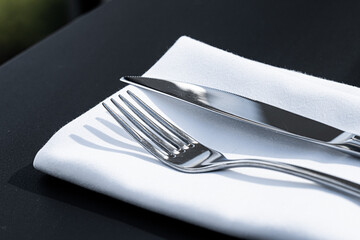 Wall Mural - Fork and knife with white napkin on table in luxury restaurant outdoors, fine dining menu for wedding or event and food catering service concept.