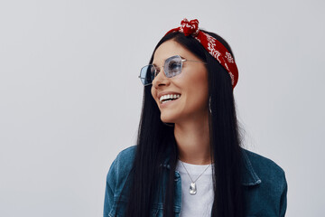 Wall Mural - Fashionable young woman in bandana smiling while standing against grey background