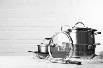 Poster - Set of clean kitchenware on white table against brick wall. Space for text