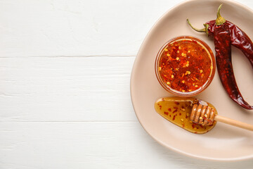 Poster - Plate with hot honey and chili peppers on light wooden background