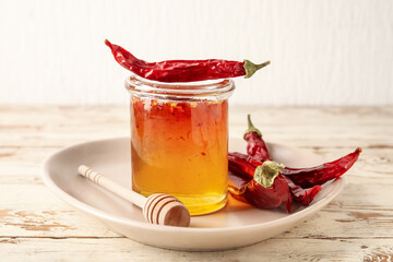 Wall Mural - Jar of hot honey and dry chili peppers on light wooden background