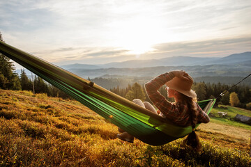 woman hiker resting after climbing in a hammock at sunset