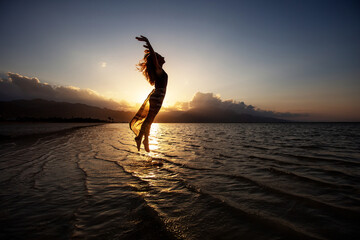 Sticker - Beautiful woman dancing by the sea at sunset