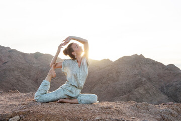 Wall Mural - Woman practicing yoga in the mountains in the desert